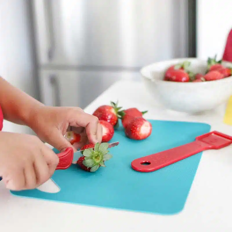 Little girl's hand cutting a strawberry using Kiddies Food Kutter