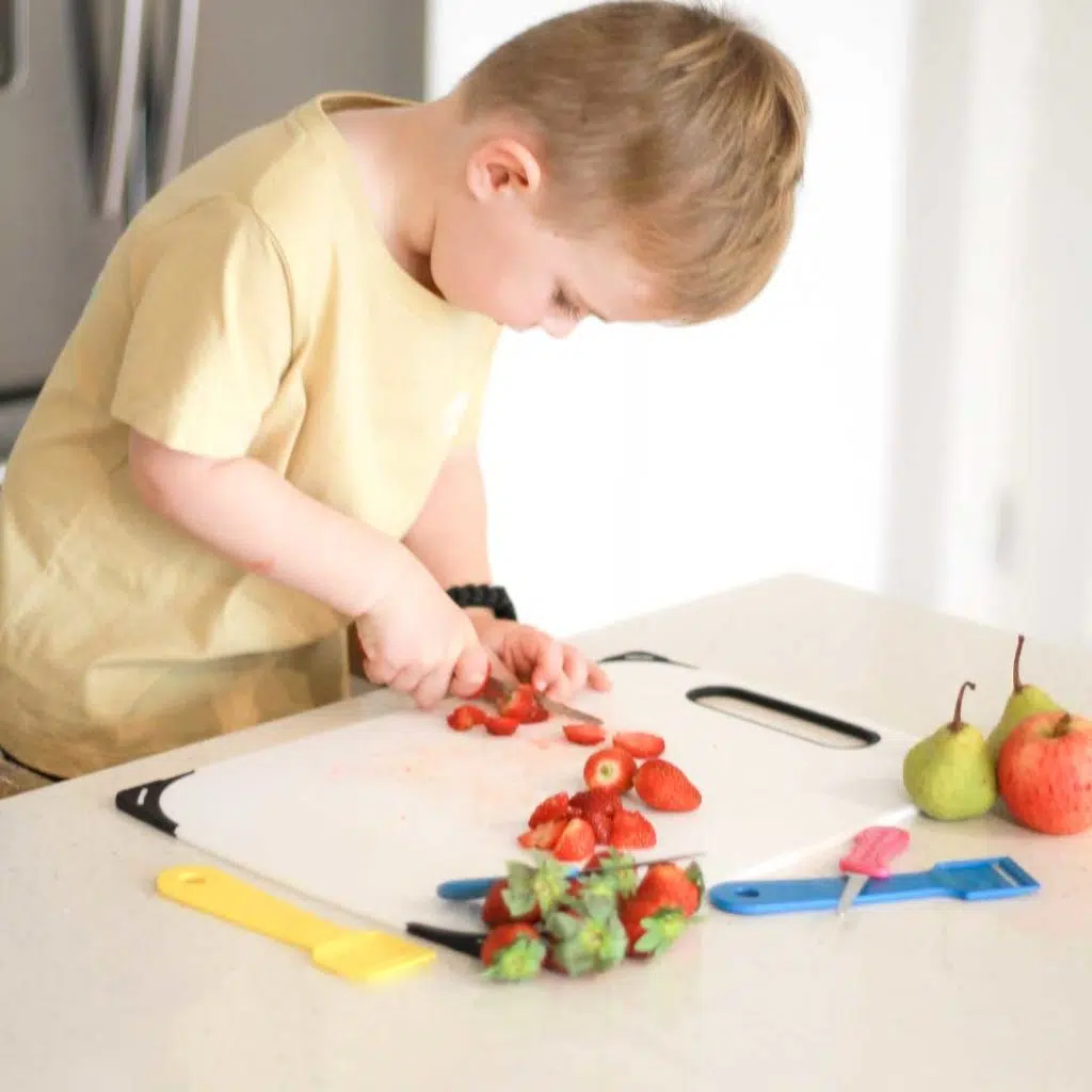 A little boy slicing a strawberry using the Safety Food Kutter