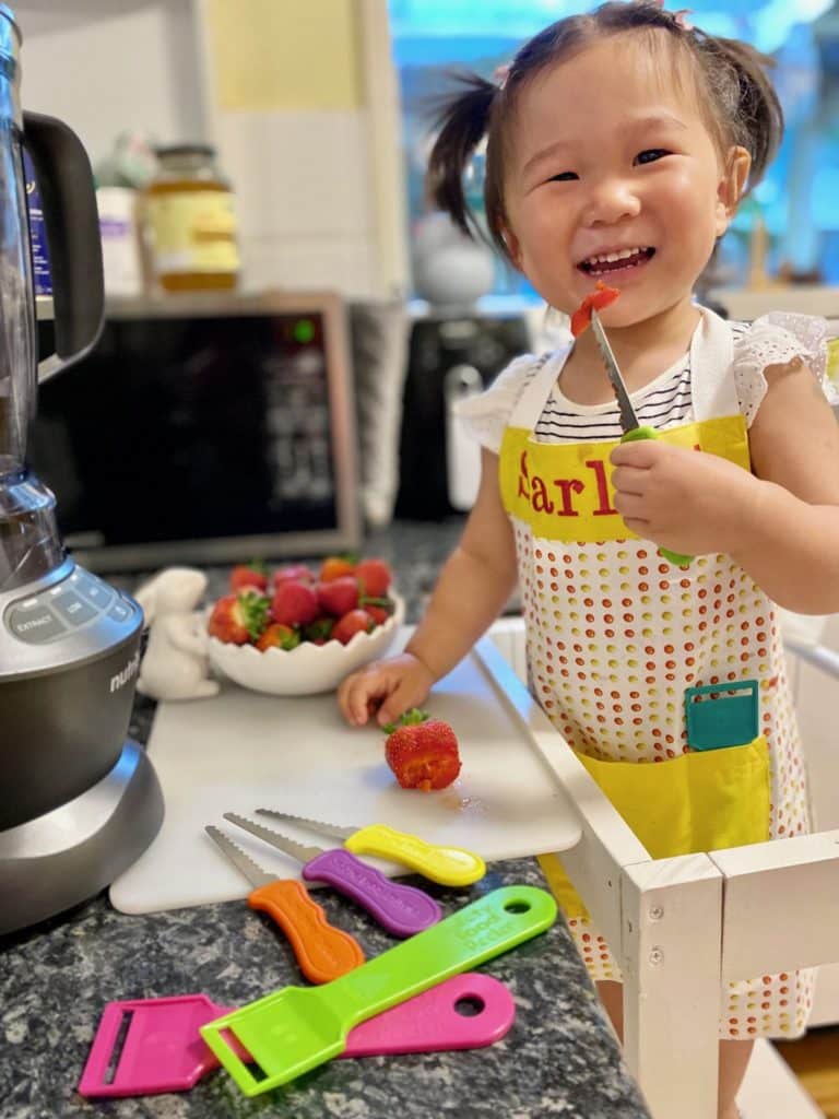 A smiling little girl holding a kid's safety knife